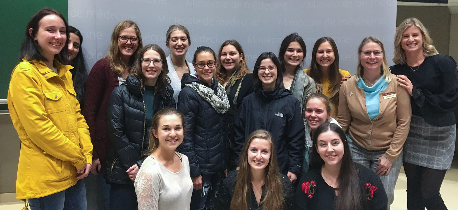 Des étudiantes et une professeure sourient devant un tableau blanc