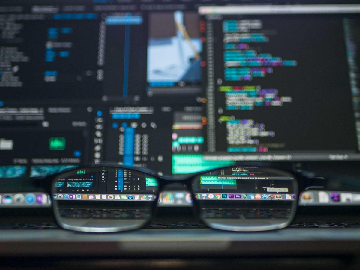 Lunettes sur le bureau devant les écrans d'ordinateur