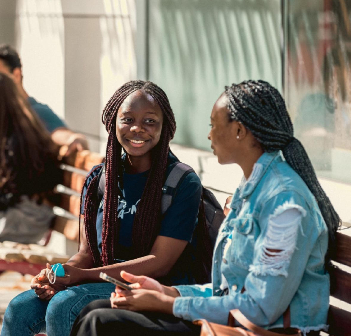 Two students sitting on a bench, chatting