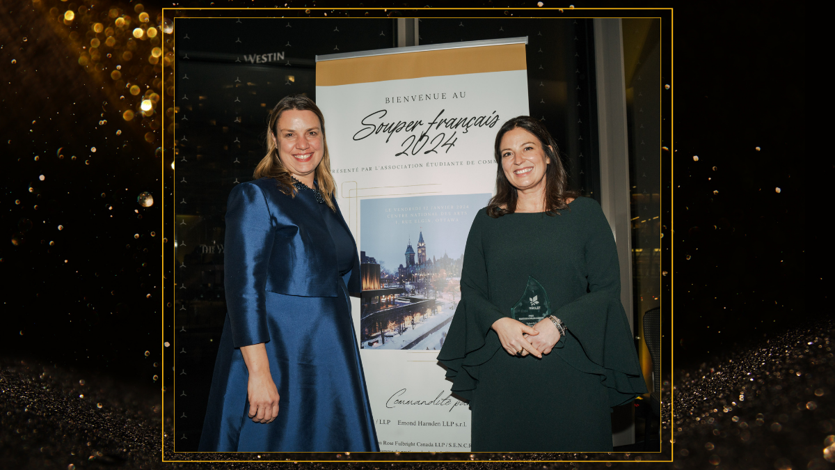Kristen Boon and Caroline Magnan stand in front of a sign for Souper français. Caroline is holding an award.