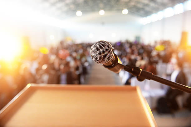 Microphone in front of a blurry seated crowd