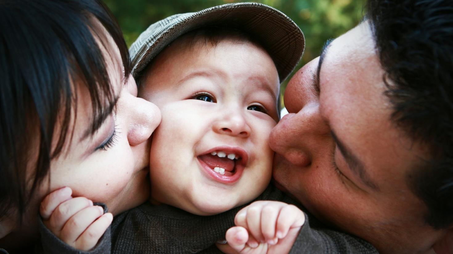 Two parents kissing child