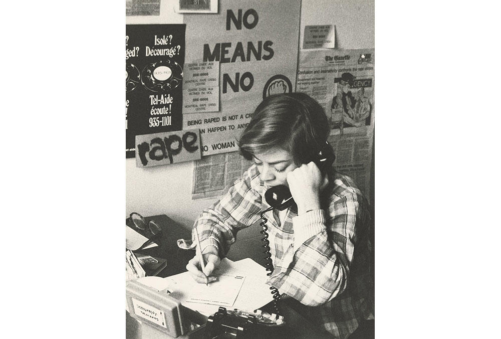 Black & white photograph of a woman on the phone at a rape crisis center