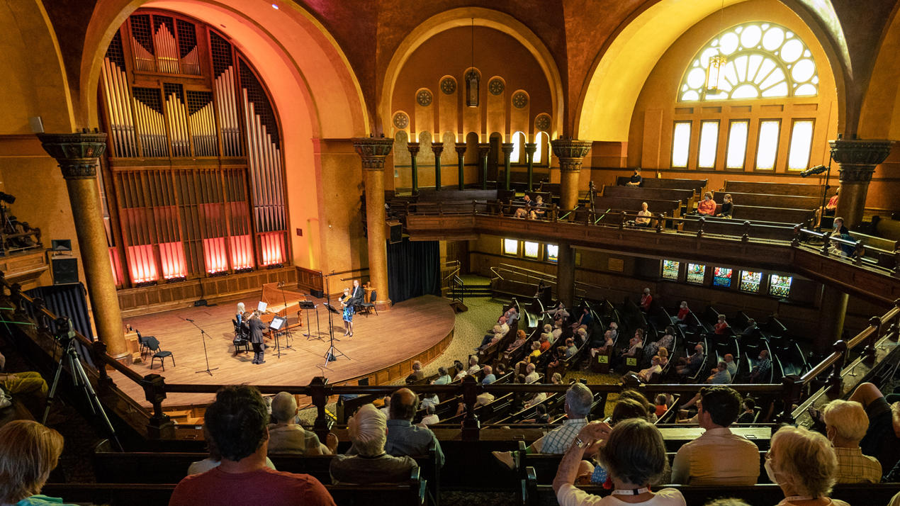 Un public à l'intérieur d'une église observe un orchestre de chambre.