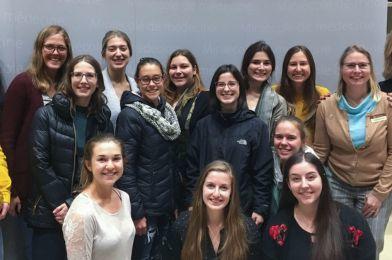 Des étudiantes et une professeure sourient devant un tableau blanc