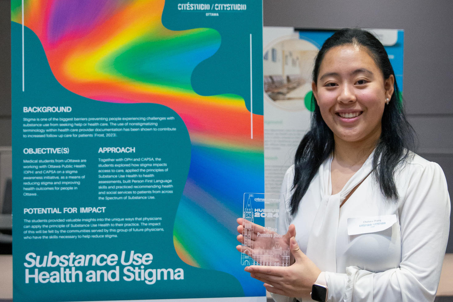 a person holds an award, standing by a poster