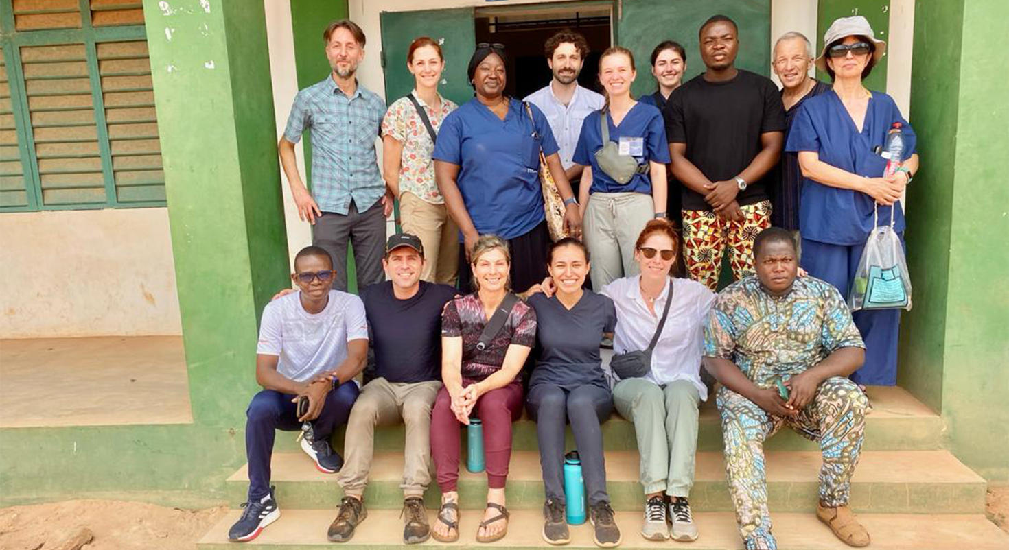 Des étudiants en médecine de l'Université d'Ottawa posent avec un groupe de personnel de santé sur les marches d'un dispensaire au Bénin.