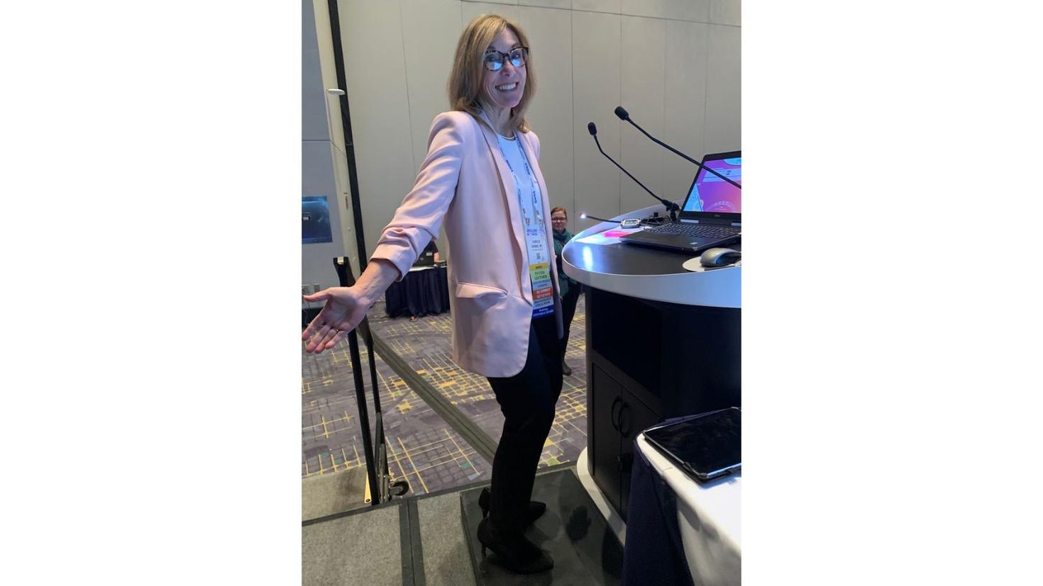 Dr. Dennie in front of her classroom desk