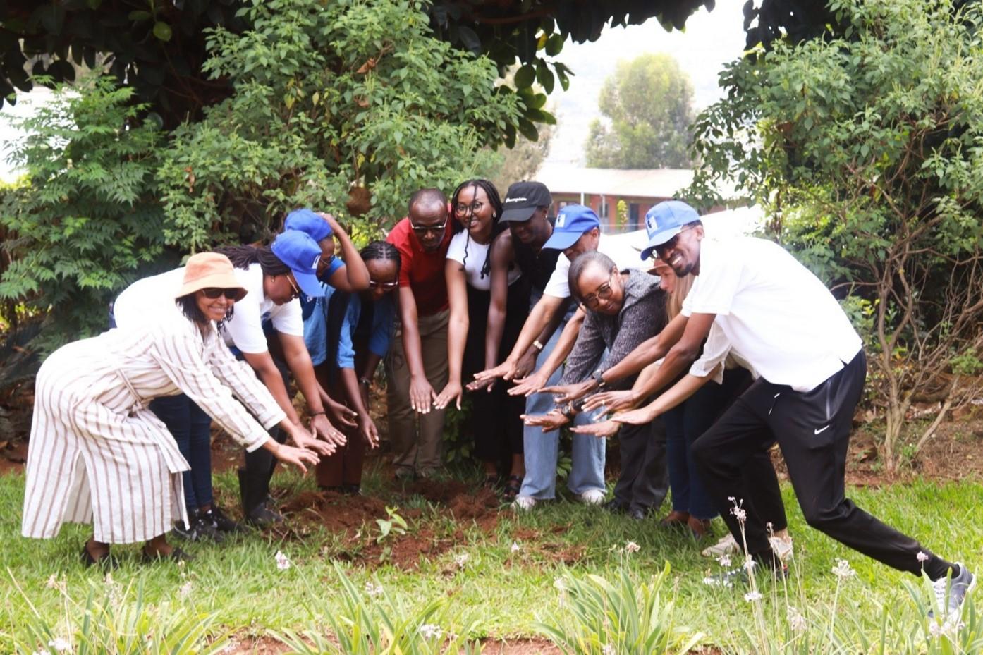 Photo d'un groupe de 10 personnes alignées dans un petit jardin de la gauche vers la droite. Chacune d'entre elle est penchée et à étendu ses deux mains vers le sol