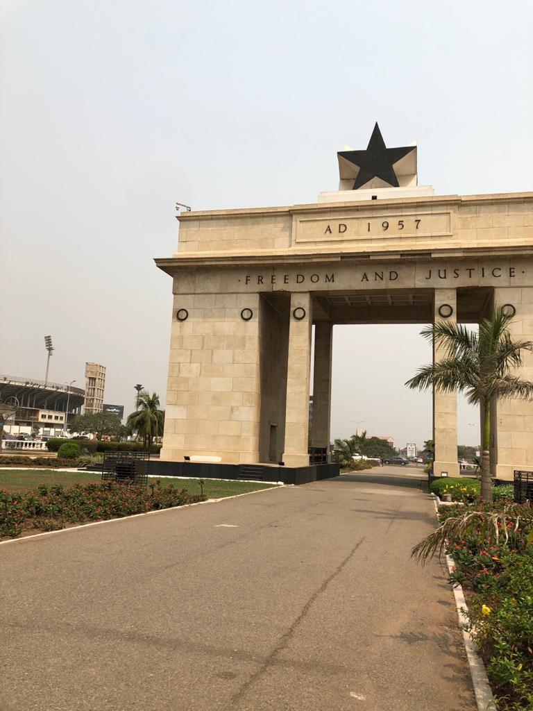 Monument in ghana on a crossroad with a star at the top.  AD 1957 written underneath the star and Freedom and justice written under AD 1957