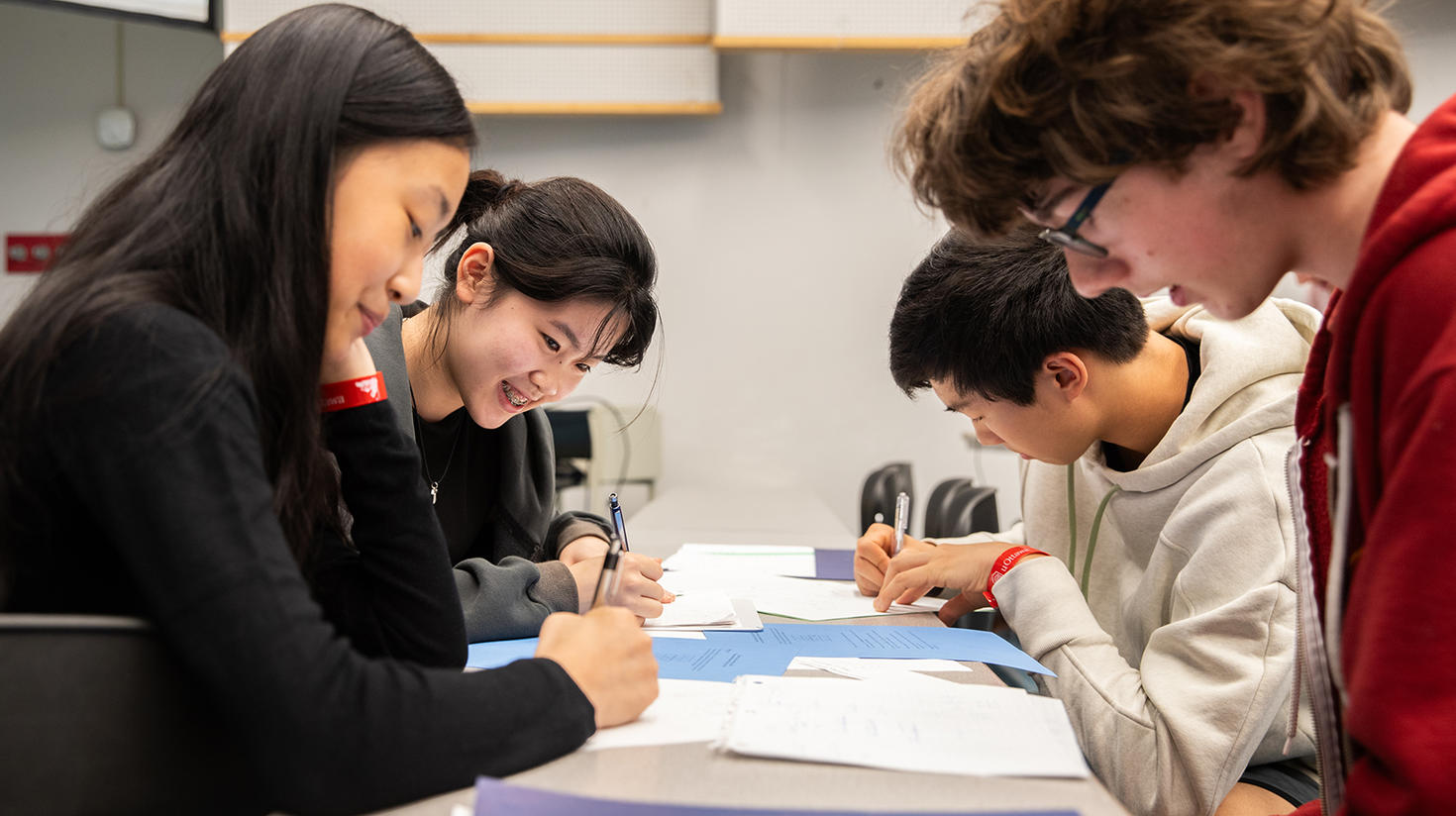 Quatre jeunes (deux garçons et deux filles) sont assis à une table et solutionnent un problème mathématique lors du camp de mathématiques 2024 de l’Université d’Ottawa.