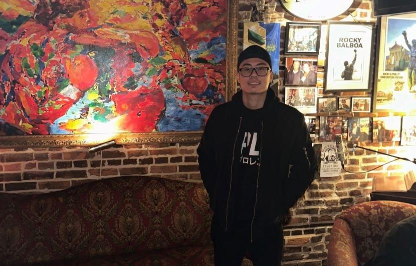 Richard Pham, étudiant et DJ, devant une toile colorée à l’intérieur d’un café.