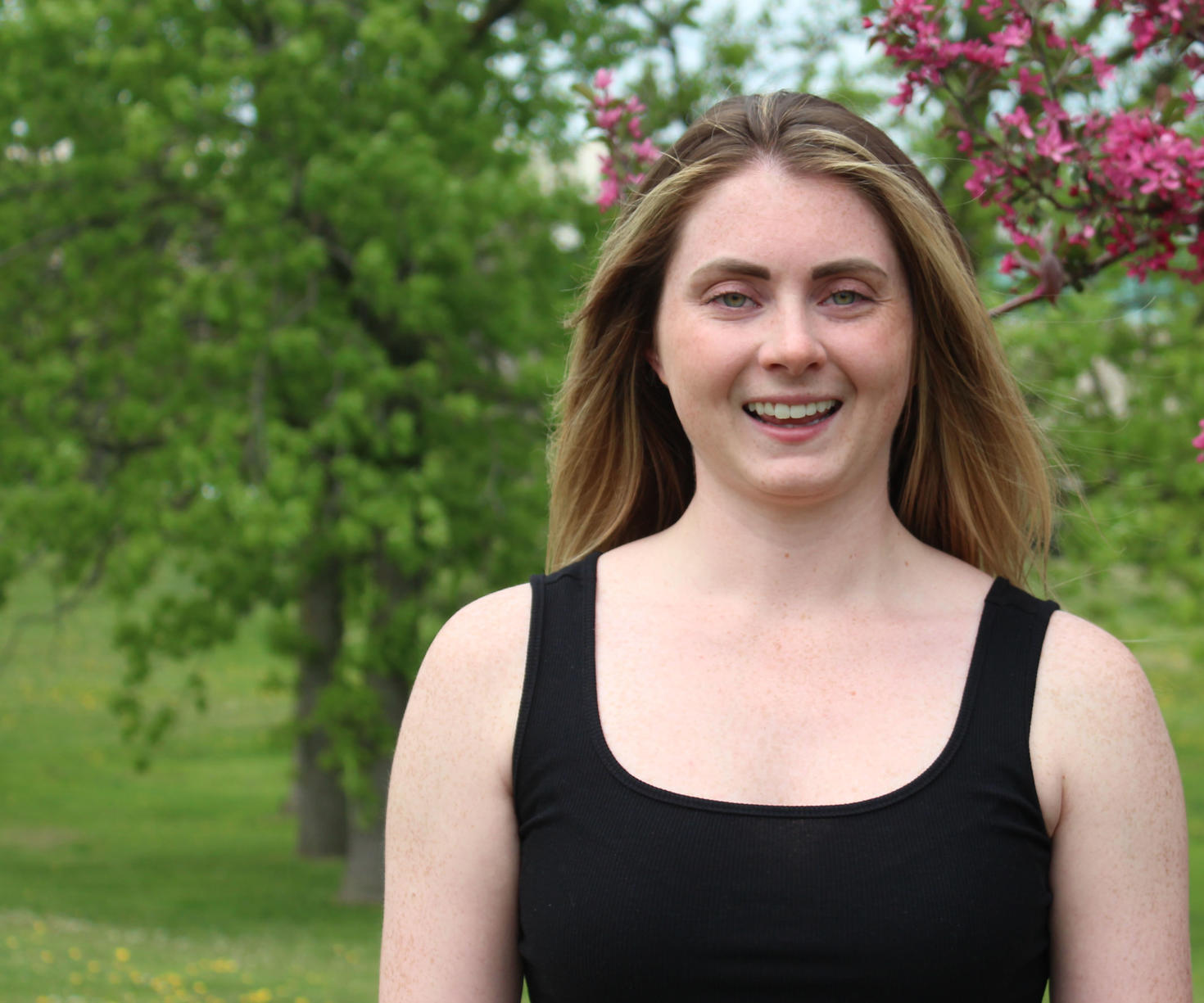 Une personne debout à l'extérieur avec des arbres en arrière-plan.