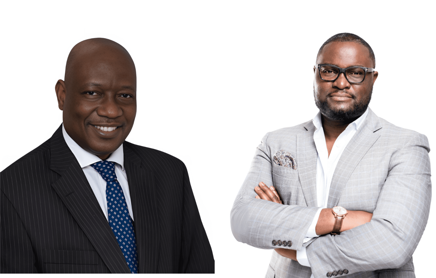 Two men pose against a white background. One man on the left wears a dark suit with a blue tie and smiles. The man on the right wears glasses and a light gray suit with arms crossed.