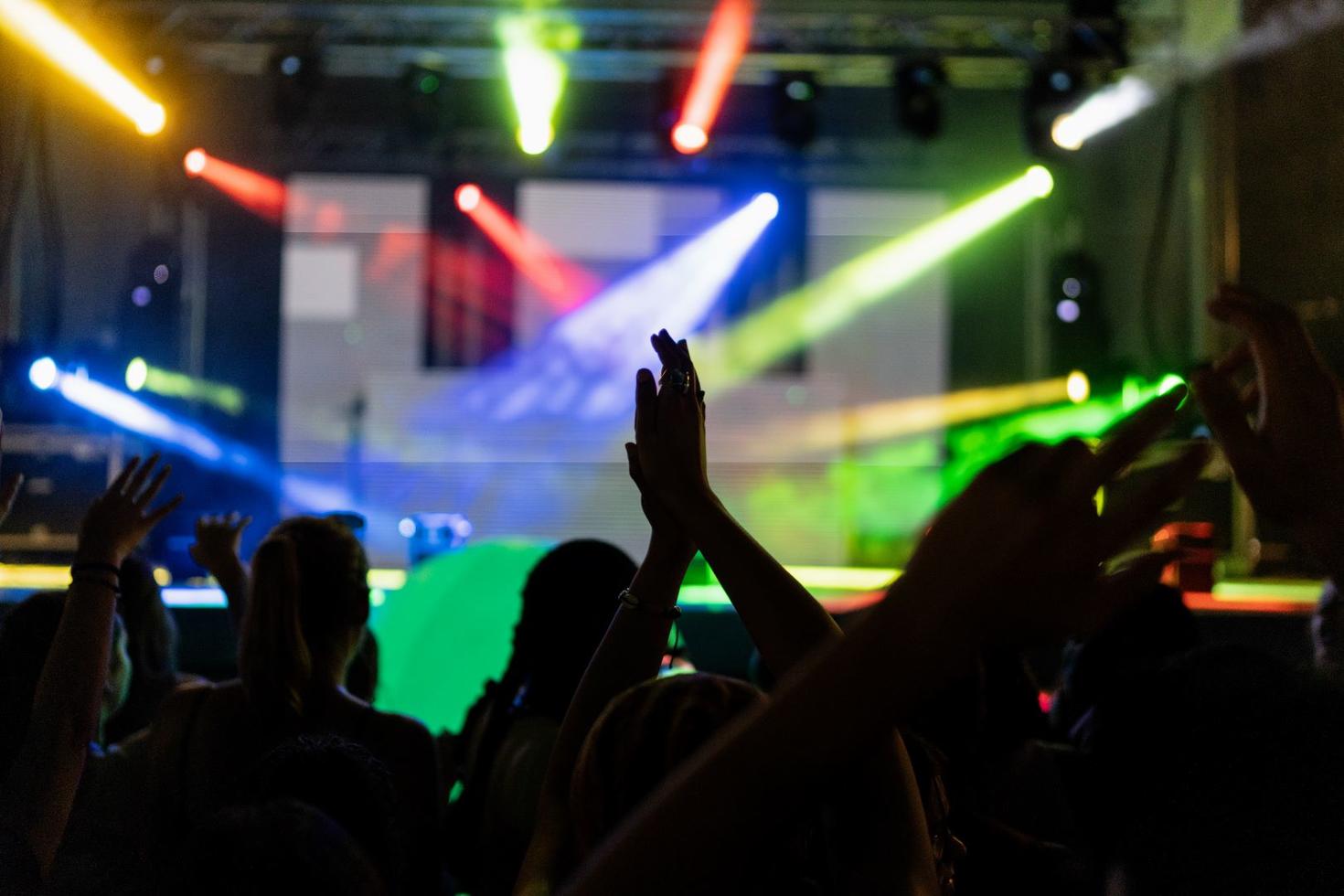 Des élèves dansant les mains en l'air, en silhouette, devant une scène éclairée.