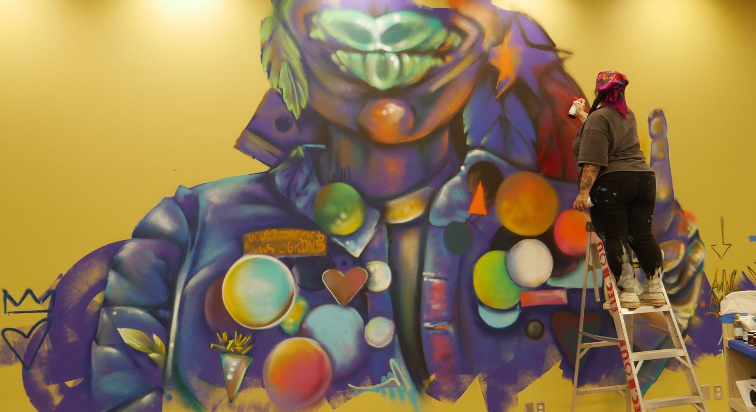 L'artiste franco-ontarienne Mique Michelle en train de peindre de nouvelles murales à la bibliothèque de l'Université d'Ottawa.