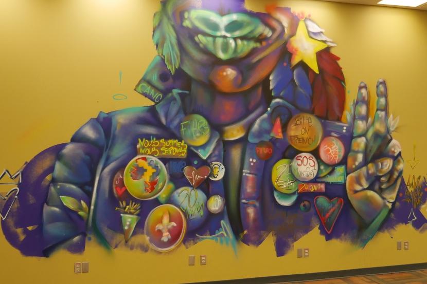 Murale de la bibliothèque de l'Université d'Ottawa, représentant une figure portant une veste couverte de badges.