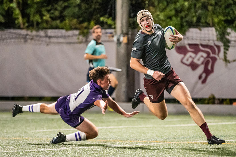 uOttawa Gee-Gees men's rugby captain James Armstrong runs with the ball past opposing players.
