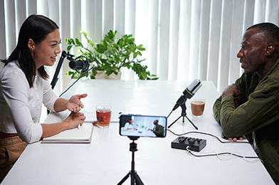 Bloggers having a discussion across a table while being filmed