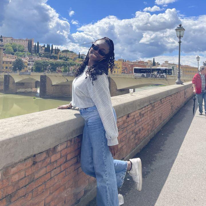 Roxane Akakpo smiles and kicks her leg by a wall overlooking the French countryside.