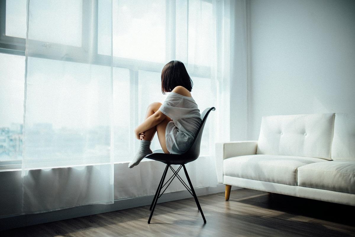Woman curled up facing windown