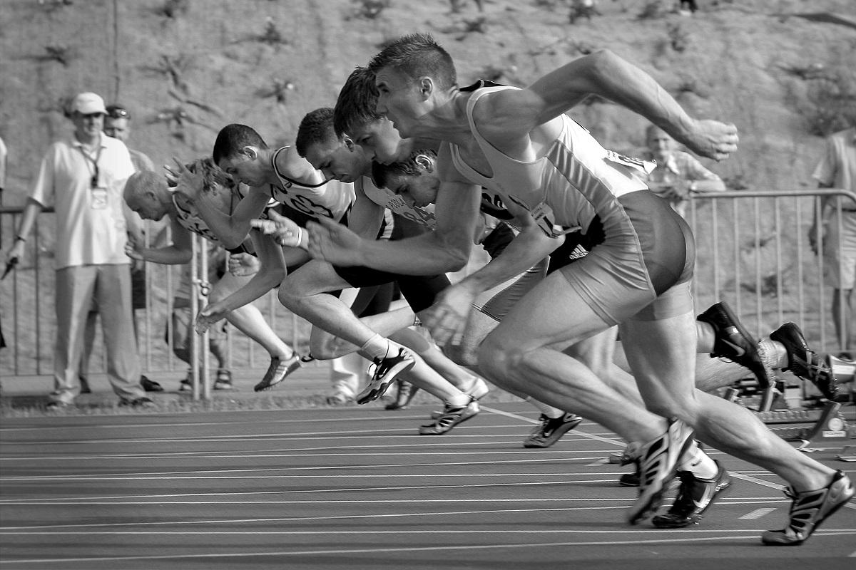 Image en noir et blanc de sprinters s'élançant du bloc de départ