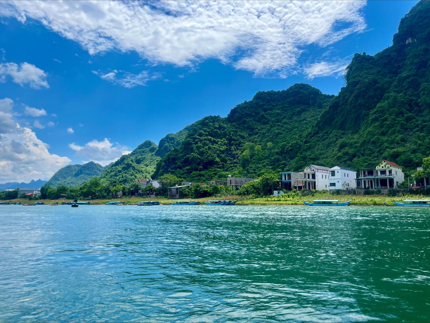 A lake surrounding a small island with habitations and mountains. Blue sky filled with clouds in the background