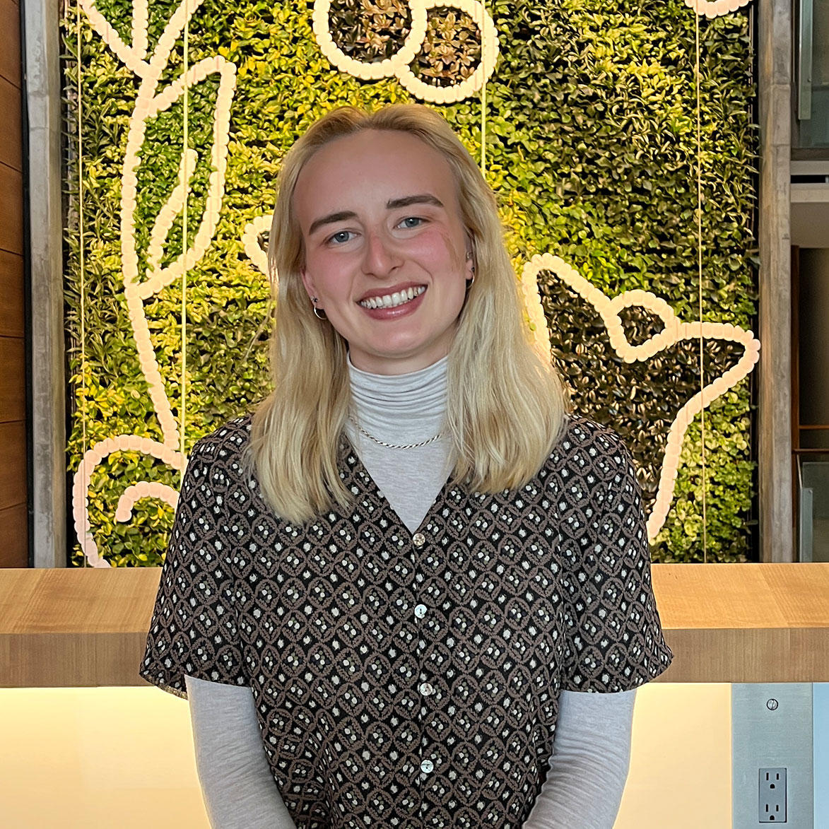Sonia Vinogradova smiles while standing against a flower wall.