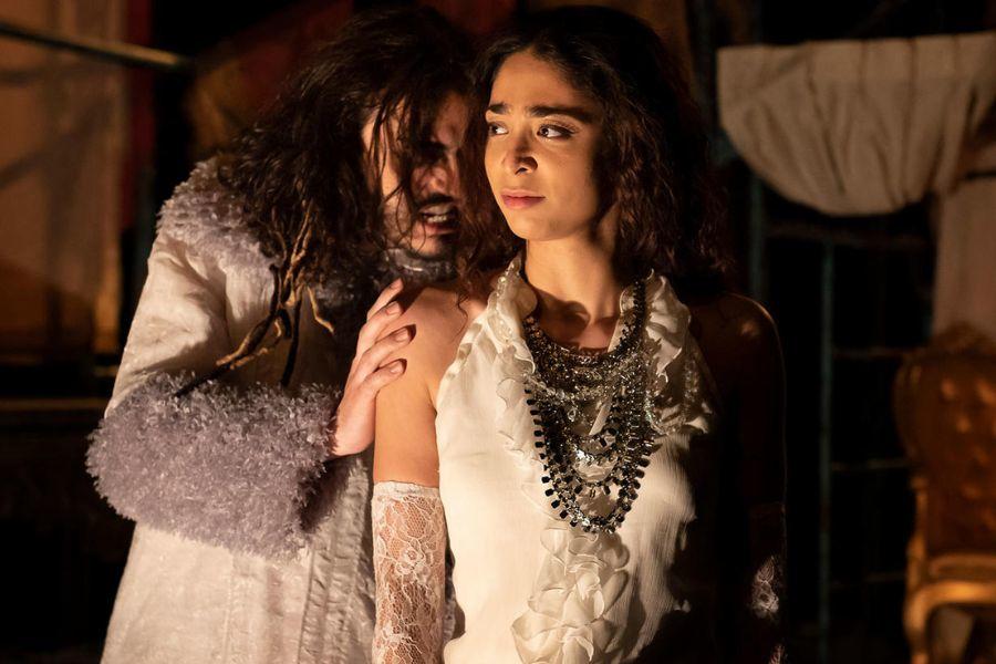  A man and woman in white clothing standing side by side on stage.