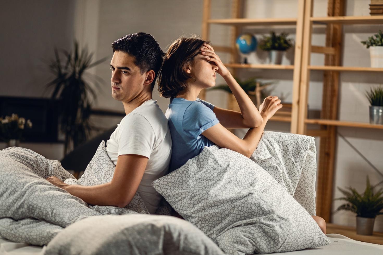 Couple assis dos-à-dos dans un lit