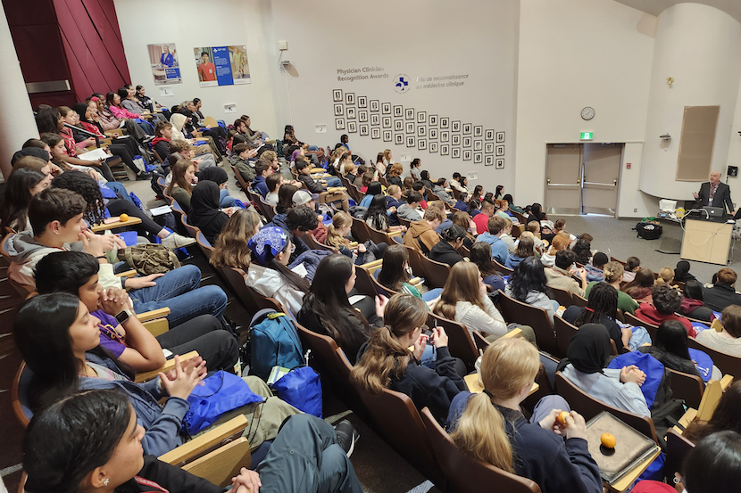Des centaines d'étudiants assis dans un amphithéâtre.