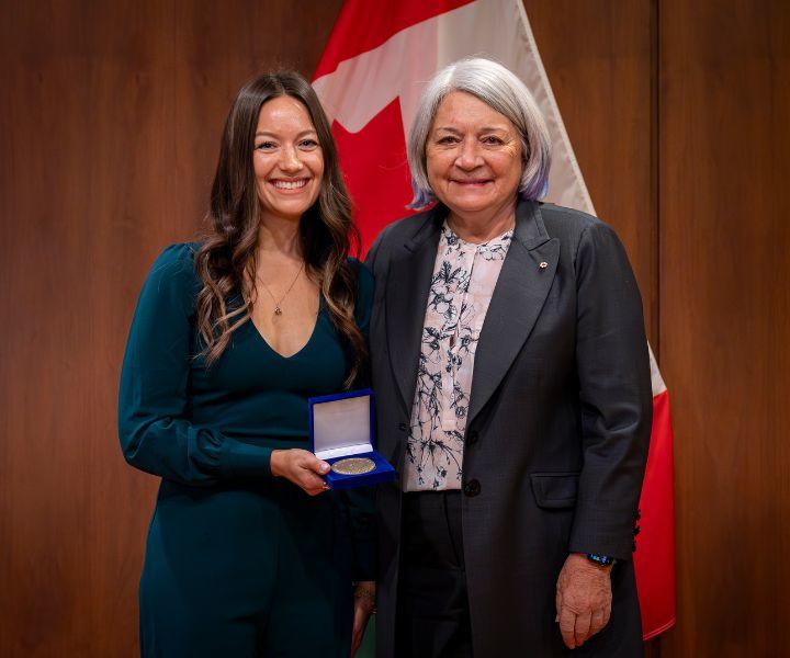 Jessica McIntyre holding a medal, standing next to the Governor General of Canada.