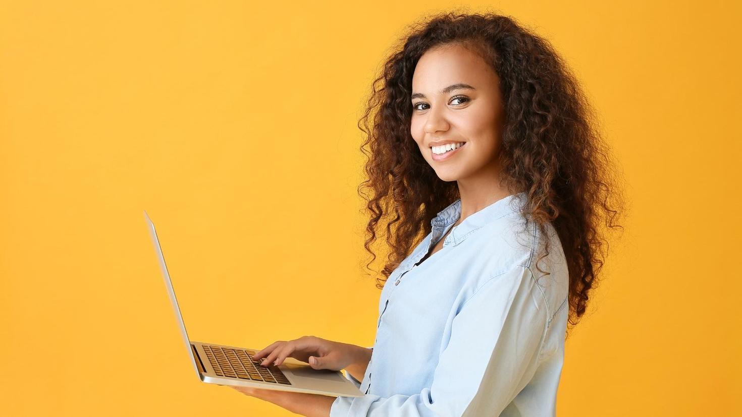 A smiling student holding a laptop.