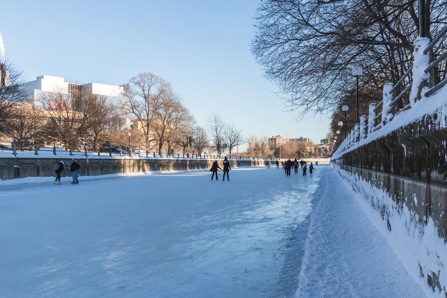 Une longue étendue de glace sur le canal Rideau avec des gens qui patinent au loin.
