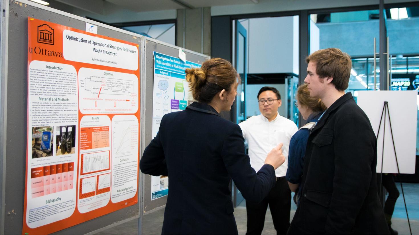 A group of persons standing in front of a poster.