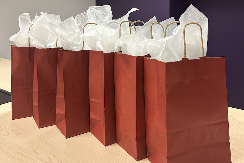Six sacs-cadeaux rouges sur une table.