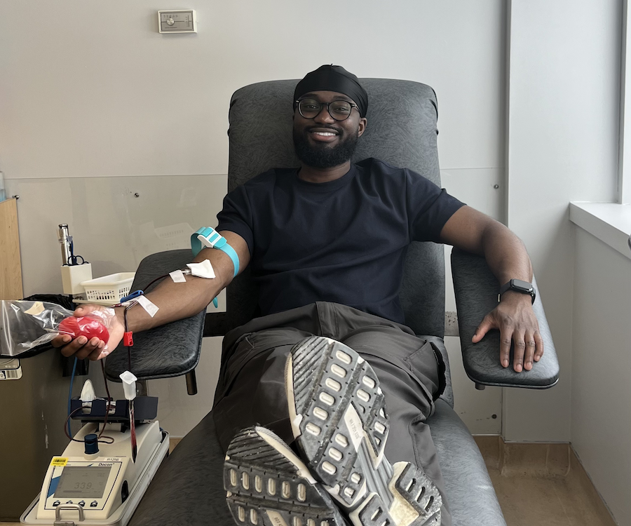a person sitting in a chair smiling as they give blood