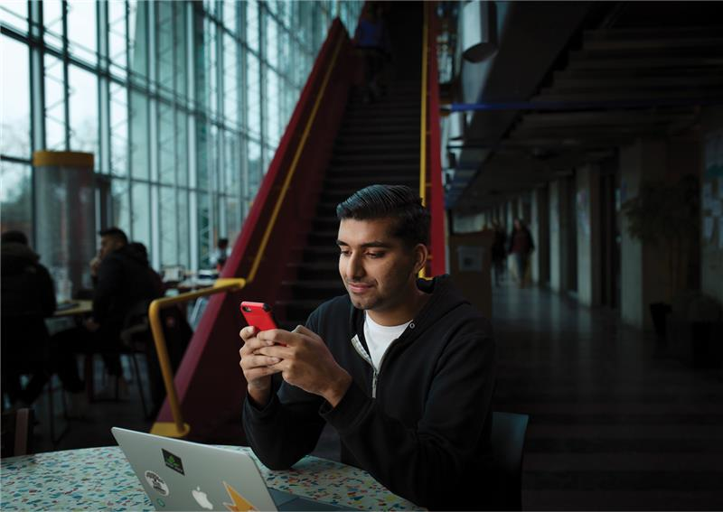 Un étudiant regarde son téléphone.
