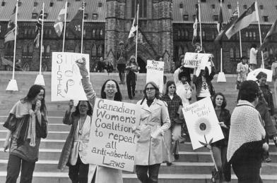 Des femmes manifestent devant la  Colline du Parlement avec des pancartes sur lesquelles on peut lire “Sin[g] Sister, Canadian Women's Coalition to repeal all anti-abortion Laws”, “Dam the Criminal Code” et “Women's Festival Today!”, Ottawa, [197?].