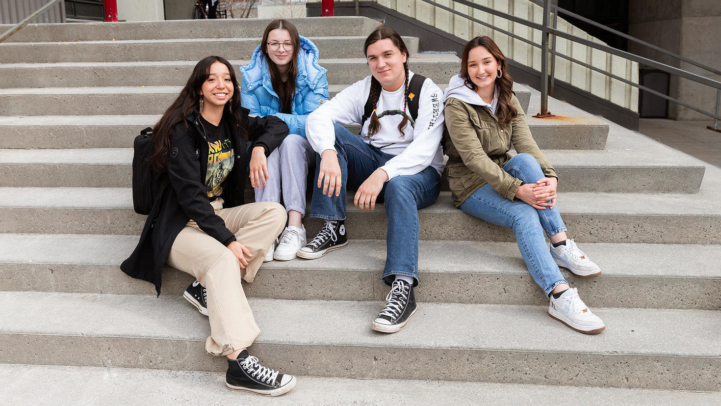 Un groupe d'étudiants et étudiantes autochtones, assis à dehors, sur le campus.