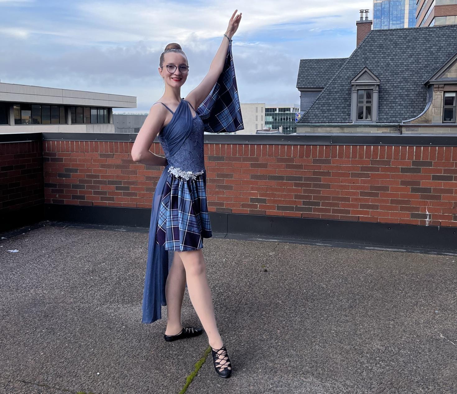 Laura Maddison porte sa tenue de danseuse des Highlands et pose sur un toit.
