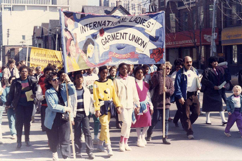 Des participantes portant une banderole de l'Union internationale des travailleurs de la confection lors d'une manifestation pour la Journée internationale de la femme à Toronto