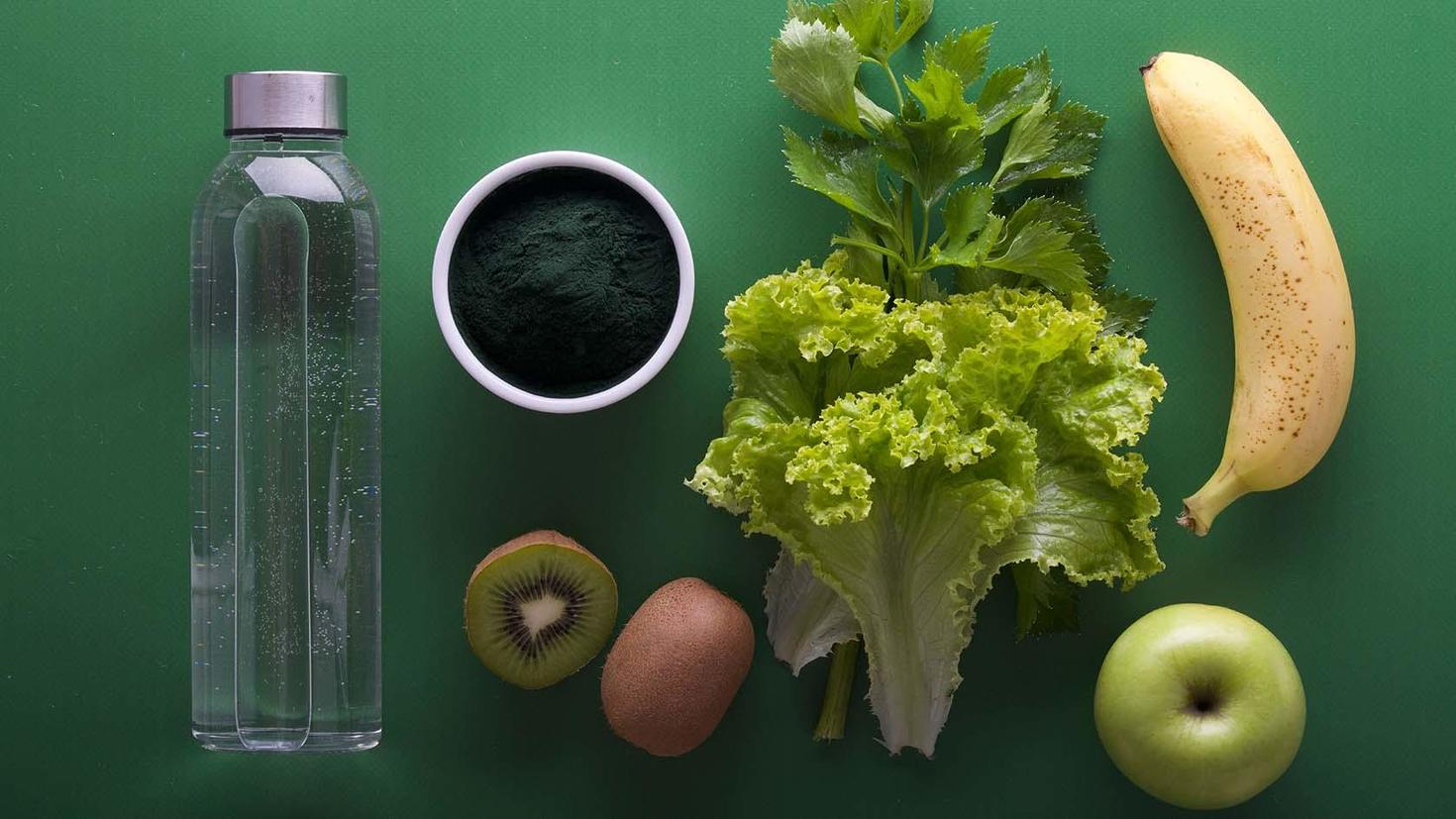 Fruits et légumes avec une bouteille d'eau sur un fond vert