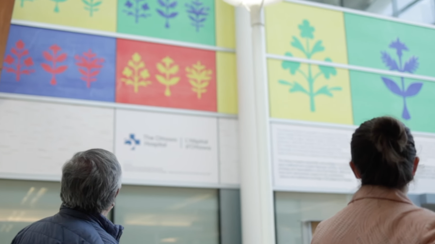 Simon Brascoupé et sa fille regardant son œuvre exposée sur un mur de L’Hôpital d’Ottawa.