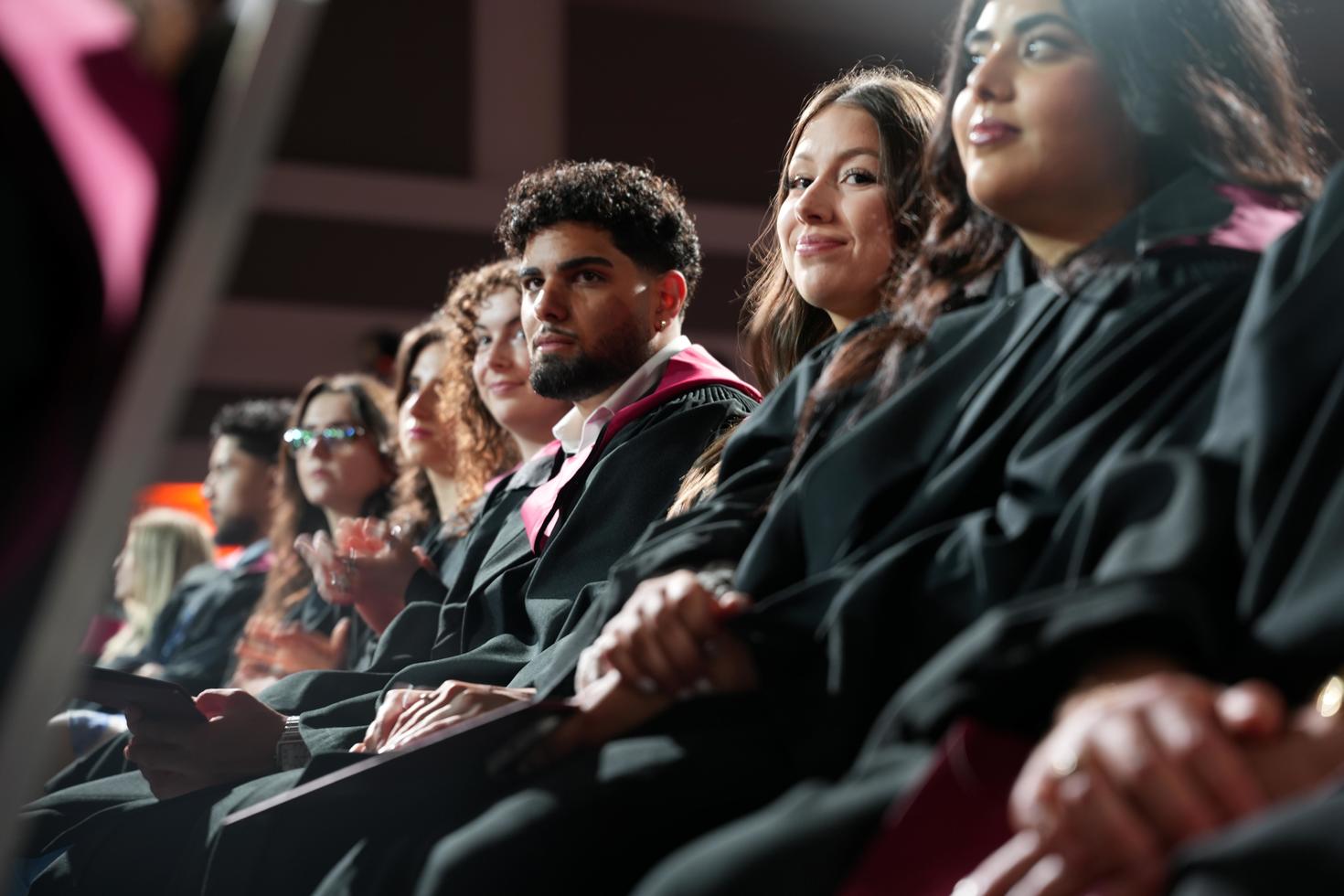 Des diplômées et diplômés assis lors de la collation des grades.