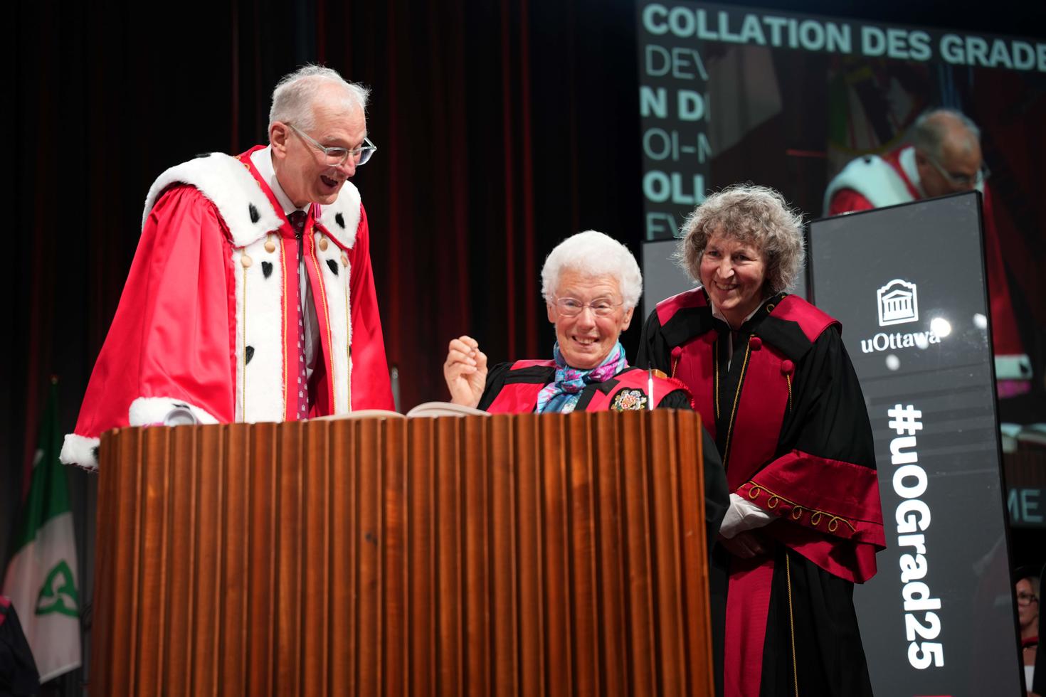 Madame Abby Hoffman signant son doctorat honorifique, en compagnie du recteur et vice-chancelier Jacques Frémont et la doyenne Lucie Thibault.