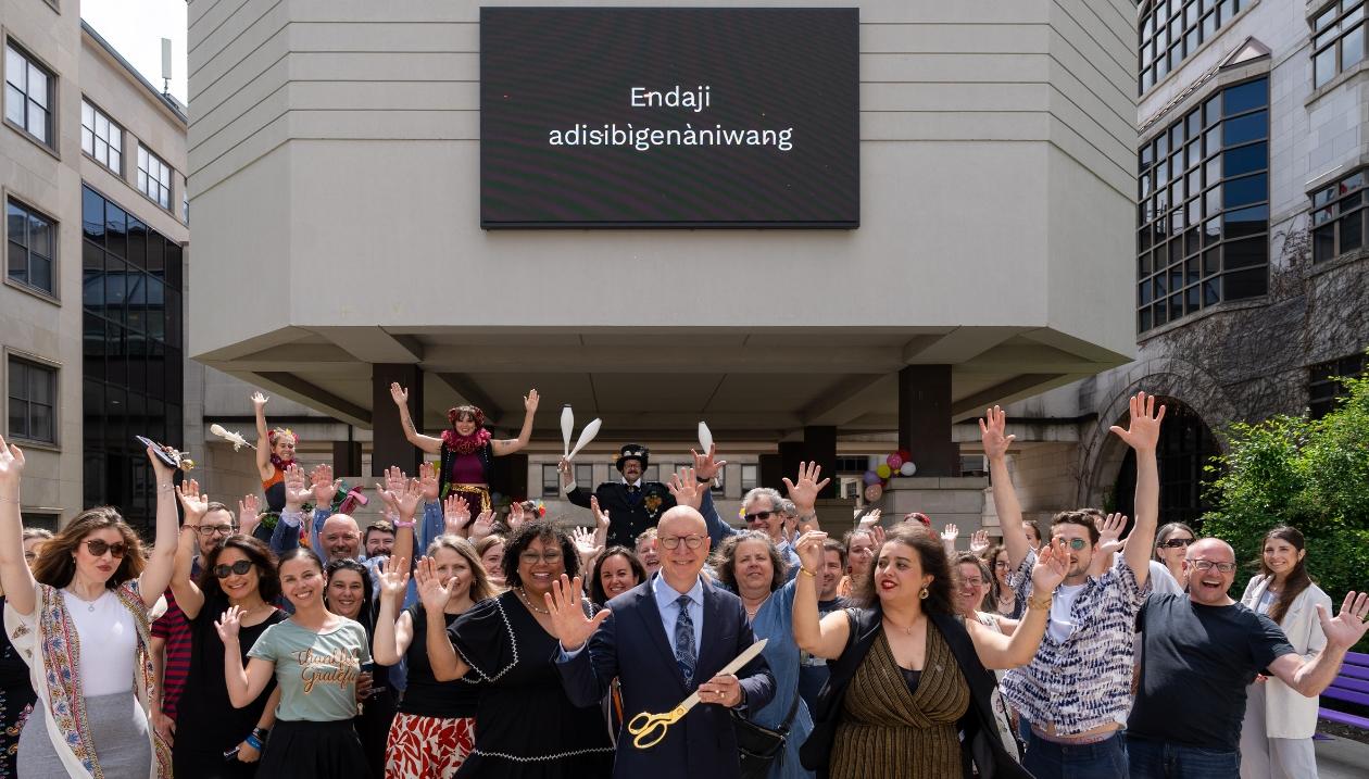 Inauguration of the Arts District at the University of Ottawa with outgoing dean Kevin Kee, joined by dignitaries, Faculty of Arts staff, and local artists, in front of the sign “Endaji adisibigenàniwang”.
