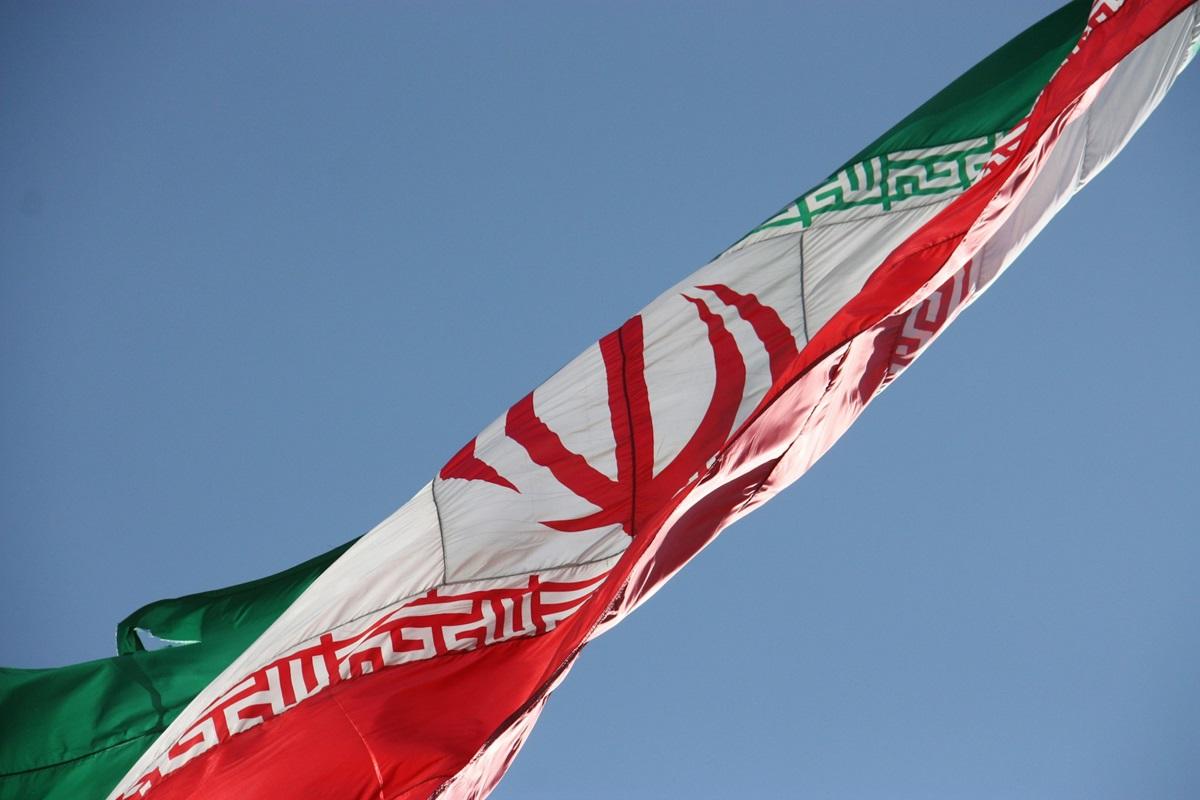 Islamic republic of Iran flag, waving over Chitgar park, lighted by evening sun