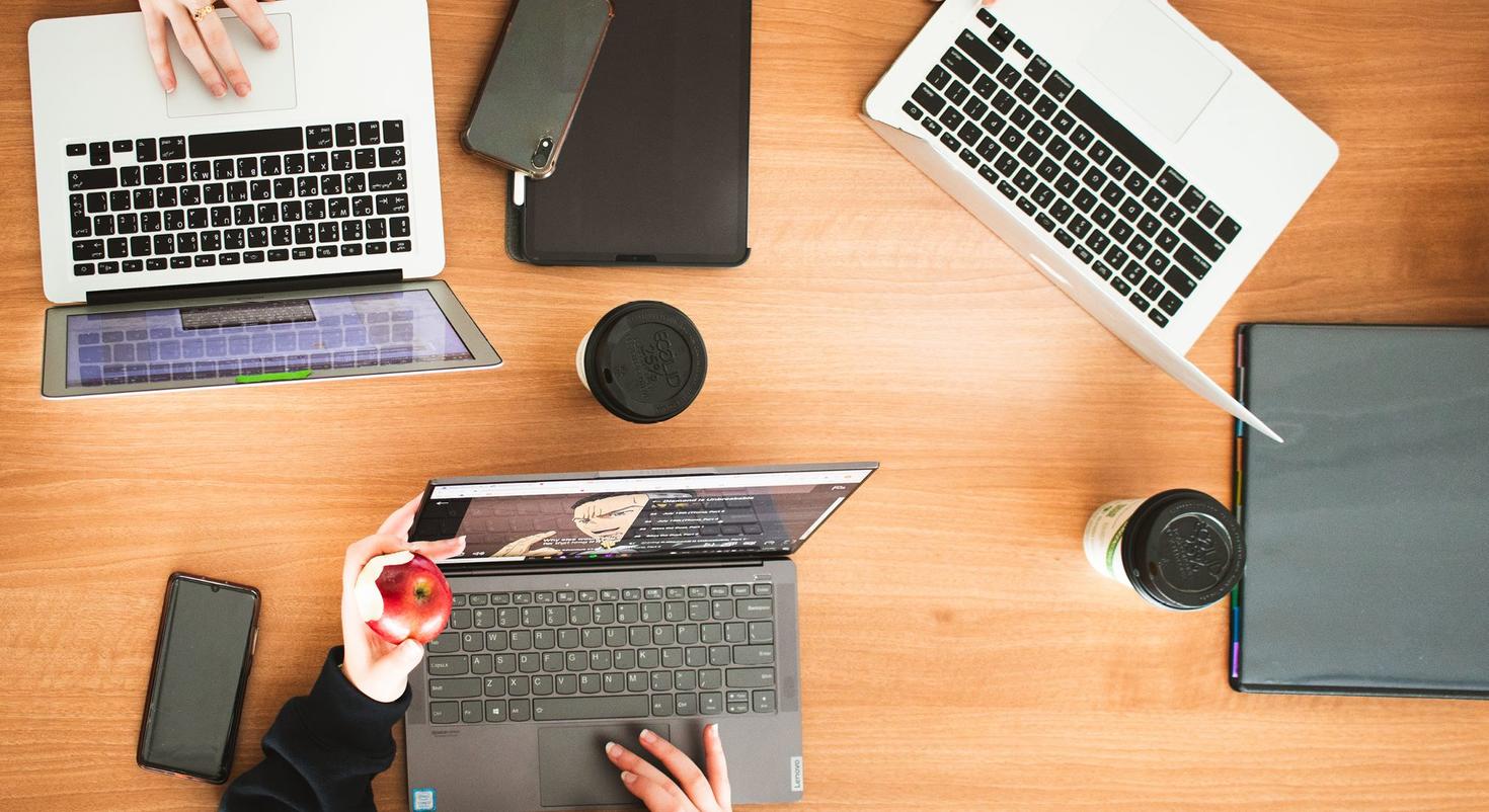 An overhead view of laptops, phones and tablets on a table.