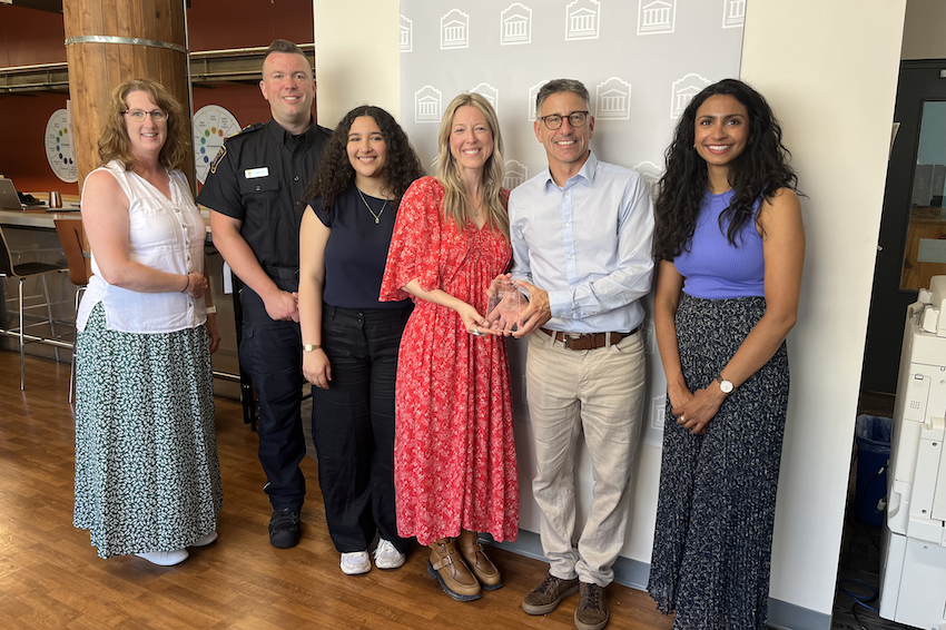 A group pf people standing around an award